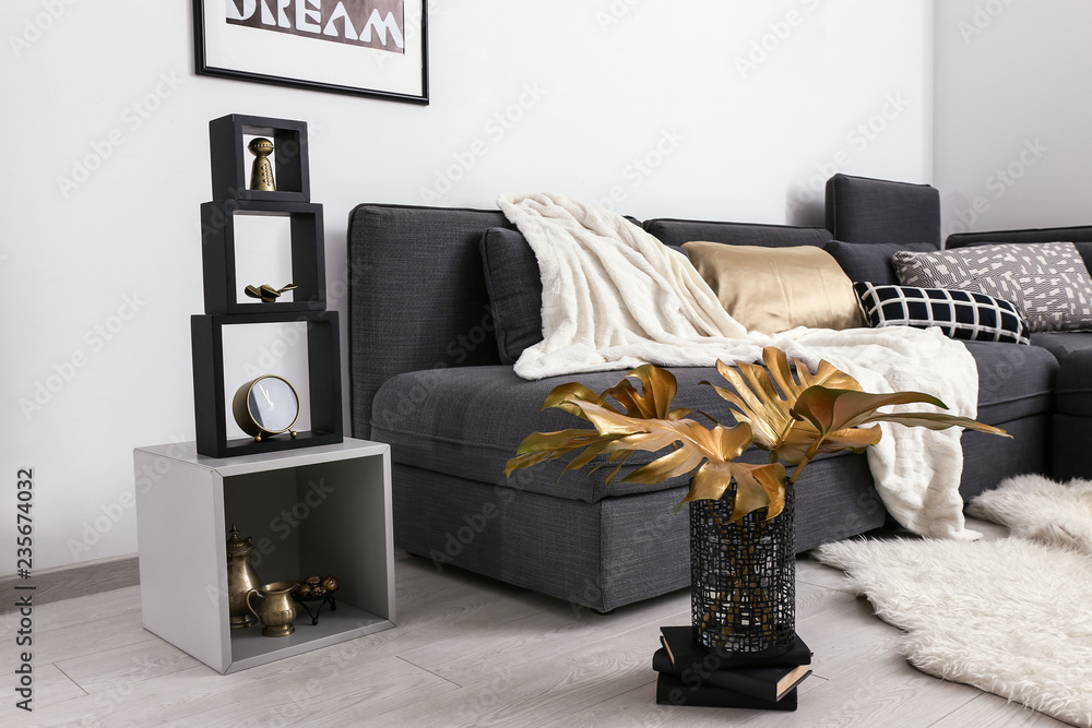 Stylish interior of room with comfortable sofa and golden decor