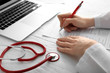 © Pixel-Shot - Female doctor filling in laboratory test request form on white table. Health care concept