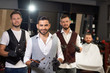 © serhiibobyk - Team of male hairdressers looking at camera in barbershop