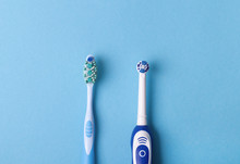 Electric And Classic Toothbrush On A Blue Background
