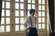 © LUMINA IMAGES - Portrait of elegant Asian man with suspenders standing by the windows.