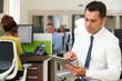 © highwaystarz - Businessman Using Digital Tablet In Modern Office