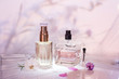 Different perfume bottles and sampler with plants on a pink floral background. Selective focus. Perfumery collection,