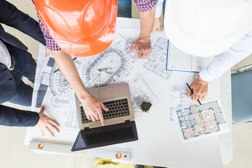 male engineers, architects working at the desk in helmets. Drawings, laptop, roulette on the desktop. Reception and supervision of building construction