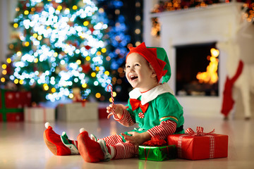 Kids at Christmas tree. Children open presents