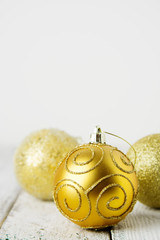 Wall Mural - Golden Christmas background with golden baubles on rustic white wooden background.