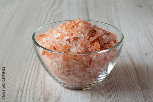 Fotografía Himalayan sea salt in a glass bowl on white wooden background, side view