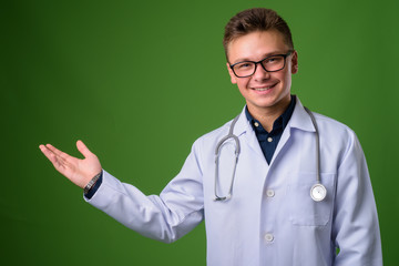 Young handsome man doctor against green background