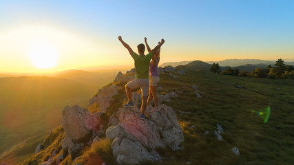 Wall Mural - AERIAL: Picturesque nature surrounding couple celebrating a successful hike.