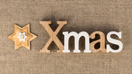 XMAS word with decorative stars on linen background