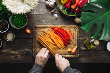 Wall Mural - Male hands prepare vegetarian thai noodles table home kitchen top view