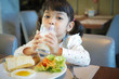 © Asada - Asian kid having a healthy breakfast in the morning. (focus on a glass of milk)