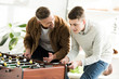 © LIGHTFIELD STUDIOS - smiling father and teen son playing table football at home