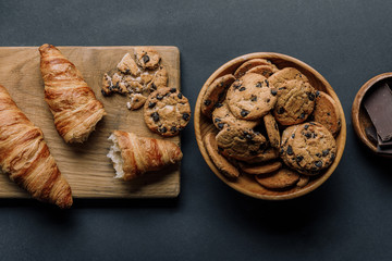 Wall Mural - flat lay with arranged croissants, chocolate and cookies on black table