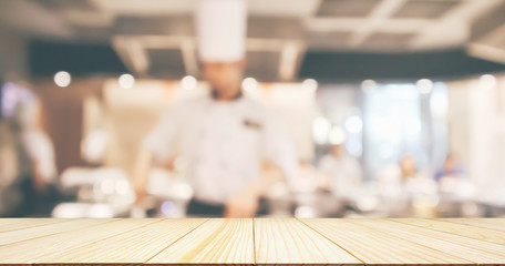 Wall Mural - Empty Wood table top with Chef cooking in restaurant kitchen blurred defocused background