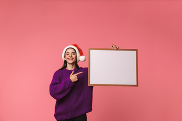 Sticker - Beautiful happy young emotional woman posing isolated over pink background holding copyspace blank.