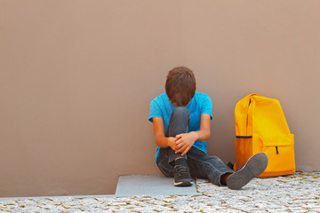 Wall Mural - Sad, tired child sitting alone on the ground outdoors