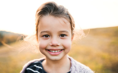 A portrait of small girl standing in autumn nature.