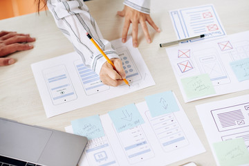 Wall Mural - crop shot from above of woman drawing on paper making new interface of app with coworker in team