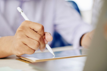 Wall Mural - closeup of man holding stylus and working on modern tablet in daylight