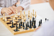 © DragonImages - Faceless people playing chess and moving figures on wooden board at table