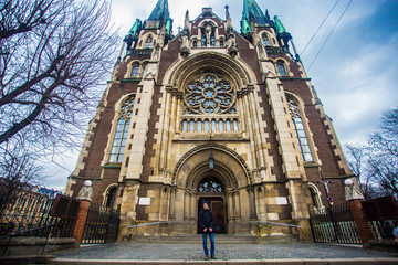 Young male tourist near old gothic church. Having great vacation