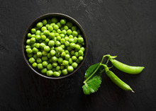 A Bowl Of Fresh Green Peas With Two Pea Pods.