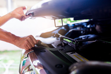 The man opened the hood of car and looking for a malfunction.