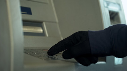 Wall Mural - Mans hand in gloves inserting pin code, stealing money from bank account, atm