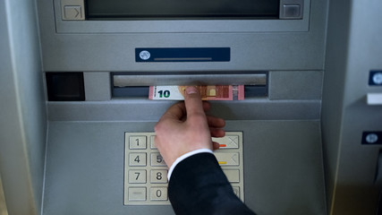 Wall Mural - Male hand taking euros from ATM top view, withdrawing cash, business trip