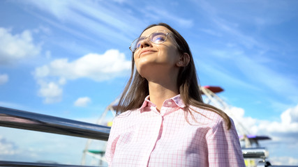 Woman smiling looking up to blue sky, taking deep breath, celebrating freedom