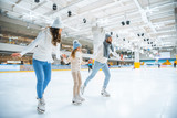 smiling family holding hands while skating together on ice rink