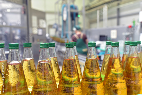 Fotografía apple juice in glass bottles in a factory for the food industry - bottling and t
