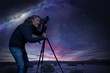 man standing at camera on tripod under a starry sky