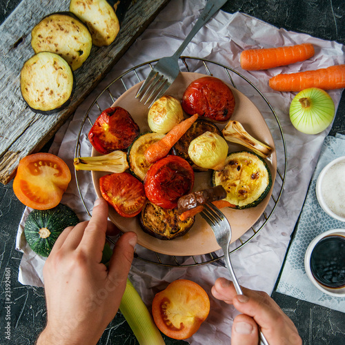Fotografie, Obraz Healthy and healthy food: grilled vegetables and men's hand with fork in the fra