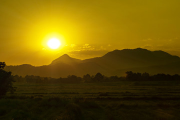 Sunset over silhouette mountain and rice field in evening