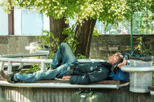 Homeless Veteran. Poor Hungry And Tired Homeless Man Ex Military Soldier Sleep In The Shade On The Bench In Urban City Street Social Documentary Concept