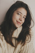 © sonyachny - Portrait of young attractive woman with no makeup in knitted sweater smiling in soft light in room. Stylish hipster girl taking selfie. Atmospheric cozy winter moments. Moody image, carefree