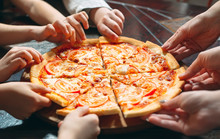 Hands Taking Pizza Slices From Wooden Table, Close Up View.