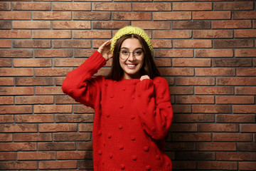 Sticker - Beautiful young woman in warm sweater with hat near brick wall