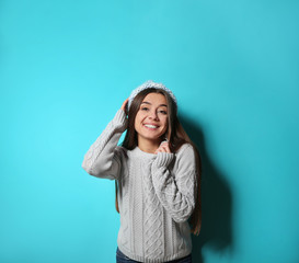 Sticker - Beautiful young woman in warm sweater with hat on color background