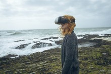 Redhead Woman Using Virtual Reality Headset On Beach