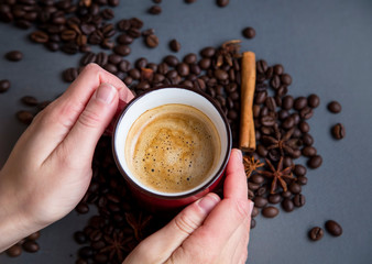 Holding cup of espresso coffee cup with coffee beans, top view