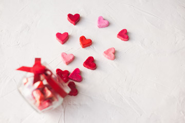 Wall Mural - Valentine's day concept. jar with hearts of sweets on a light background, top view.selective focus