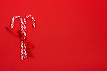 Festive Christmas background with two candy canes and ribbon on red background. Place for text.