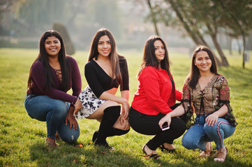 Wall Mural - Group of four happy and pretty latino girls from Ecuador posed at street.