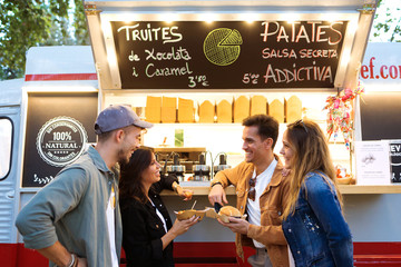 Attractive young group of friends visiting and buying fast food in eat market in the street.