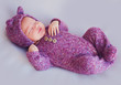cute newborn baby girl in purple knitted overall is sleeping peacefully
