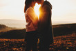 © Strelciuc - Side view of crop young man and woman touching noses while standing on background of amazing countryside and beautiful sundown sky.Crop couple against sunset sky