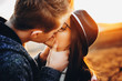 © Strelciuc - Young man kissing pretty girlfriend passionately while standing on blurred background of nature during sunset.Young couple kissing in countryside